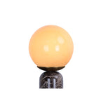 Gros plan du globe en verre allumé de la lampe LAZIO Sphère et du haut de son socle en marbre veiné.
