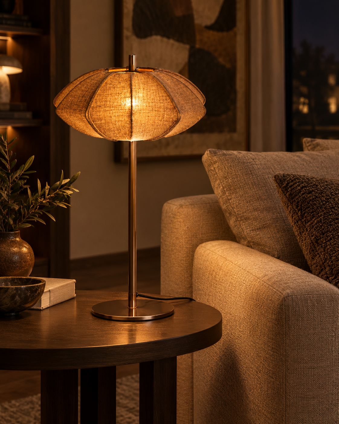 Lampe PARIS Disque taupe allumée sur une table d’appoint près d’un canapé, dans un salon à l’ambiance chaleureuse.