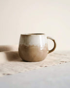 Main tenant le mug DUNES en céramique beige et caramel, fait main