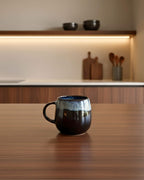 Mug UNIVERS bleu profond sur table en bois, céramique portugaise artisanale, ambiance douce et moderne.