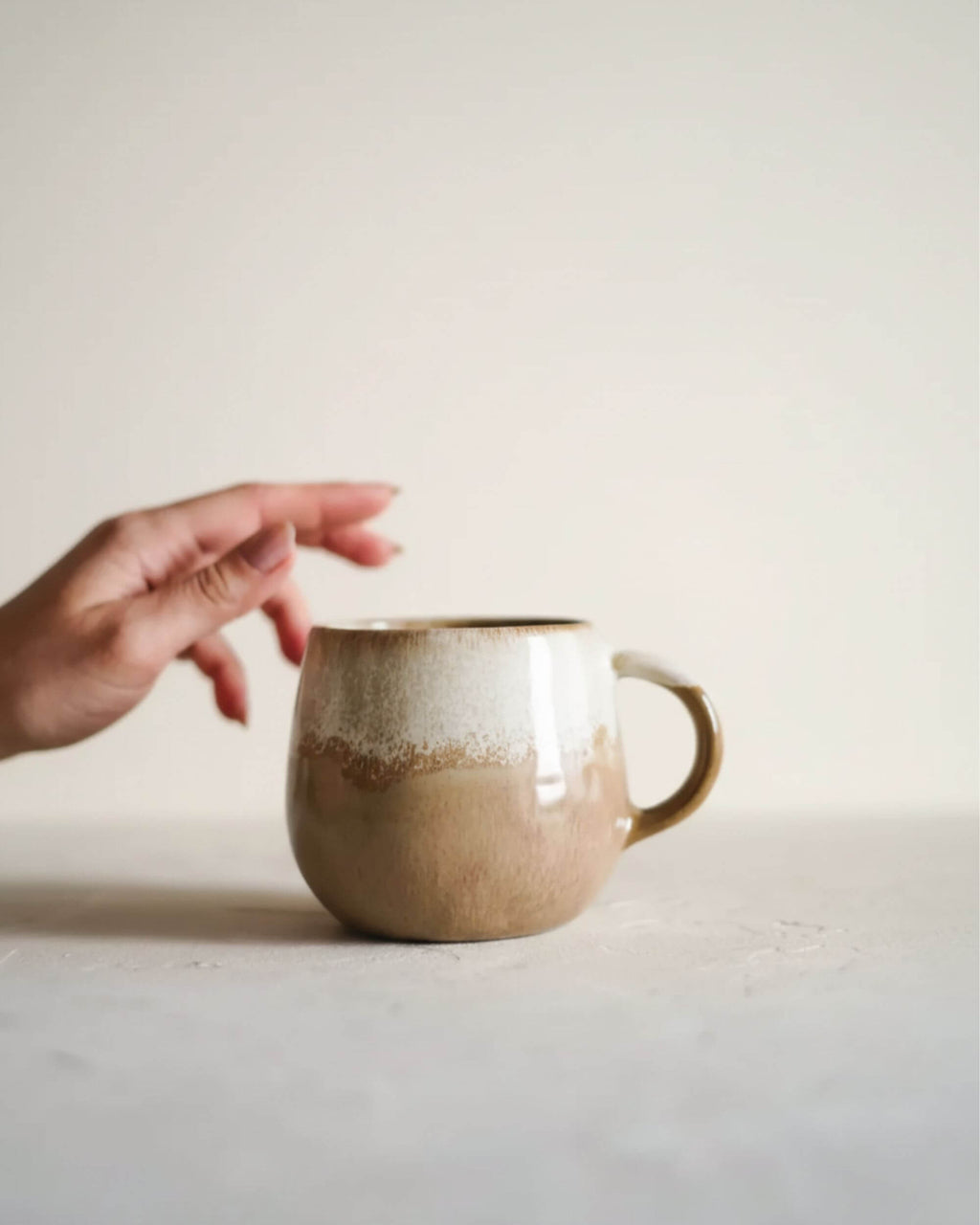 Mug DUNES de la collection CerAmor Cerâmica, ambiance chaleureuse, plan avec main