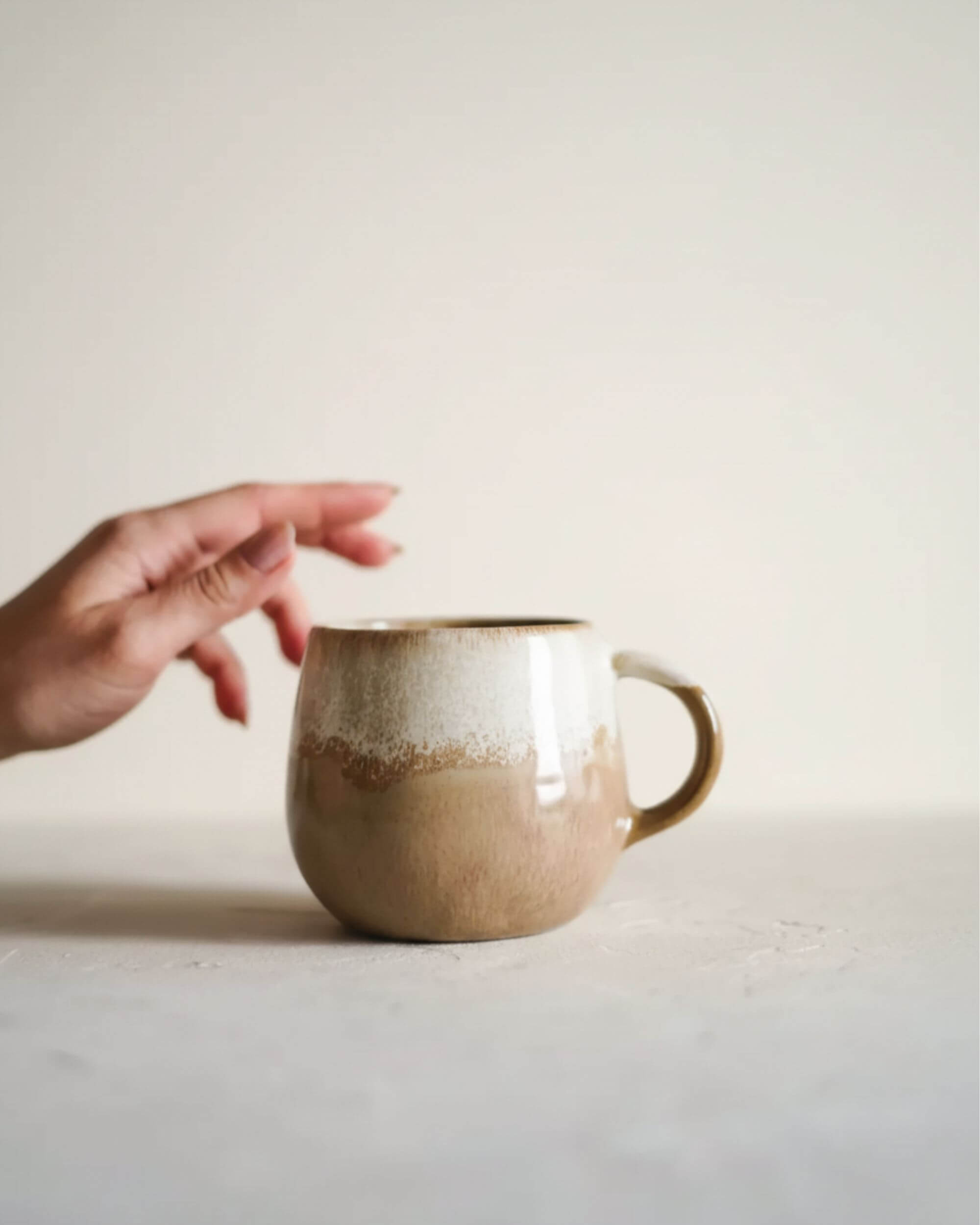 Mug DUNES de la collection CerAmor Cerâmica, ambiance chaleureuse, plan avec main