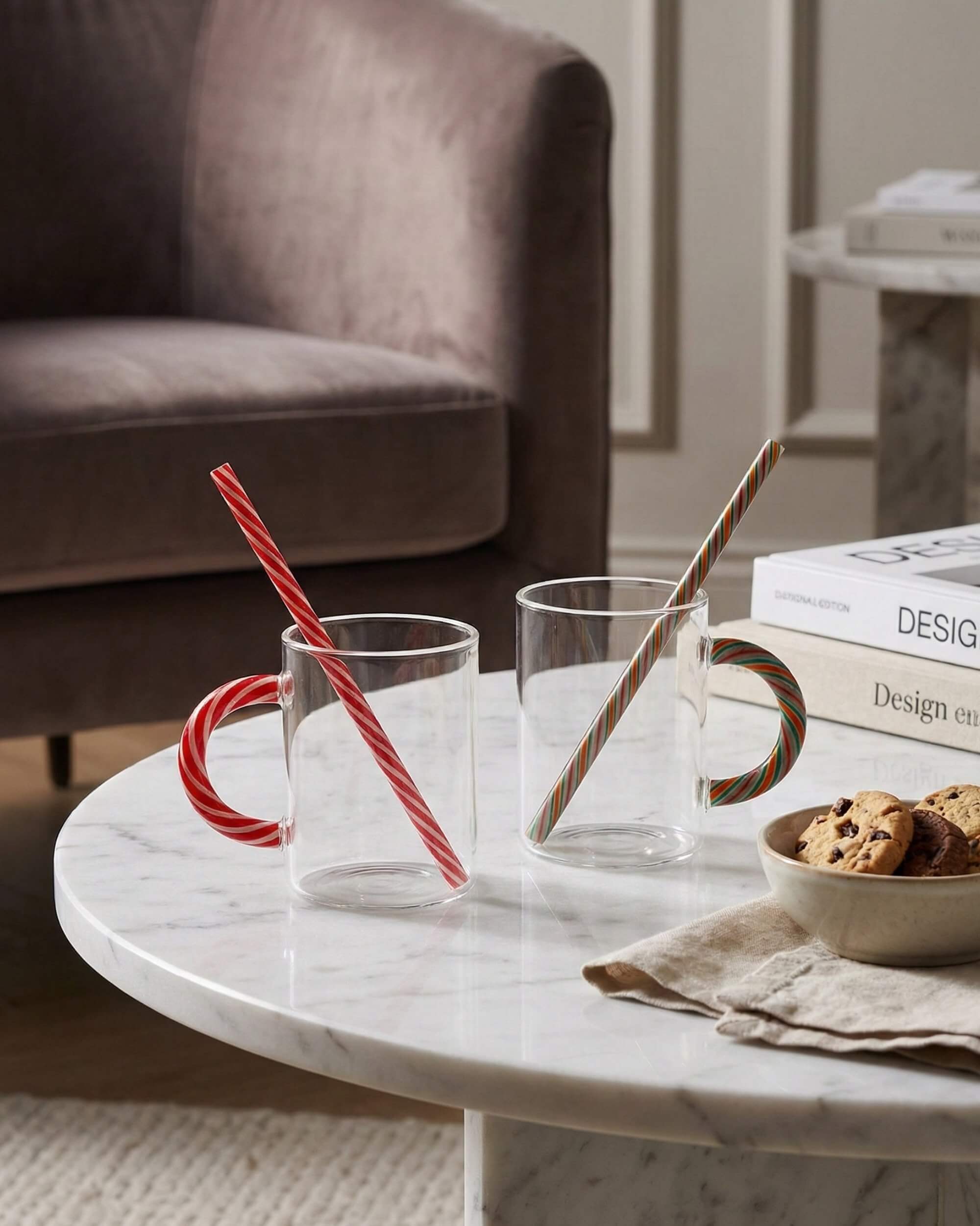 Duo de tasses en verre transparent Candy Cane avec anses et pailles rayées motif sucre d'orge. Ambiance festive et cosy sur table en marbre avec des cookies.