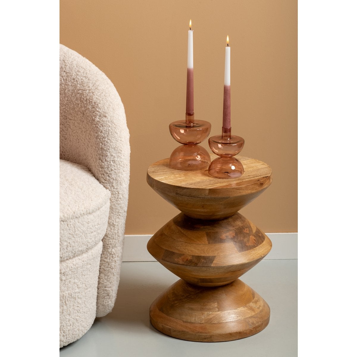 Table totem en bois disposée à côté d'un fauteuil dans un salon à la décoration naturelle