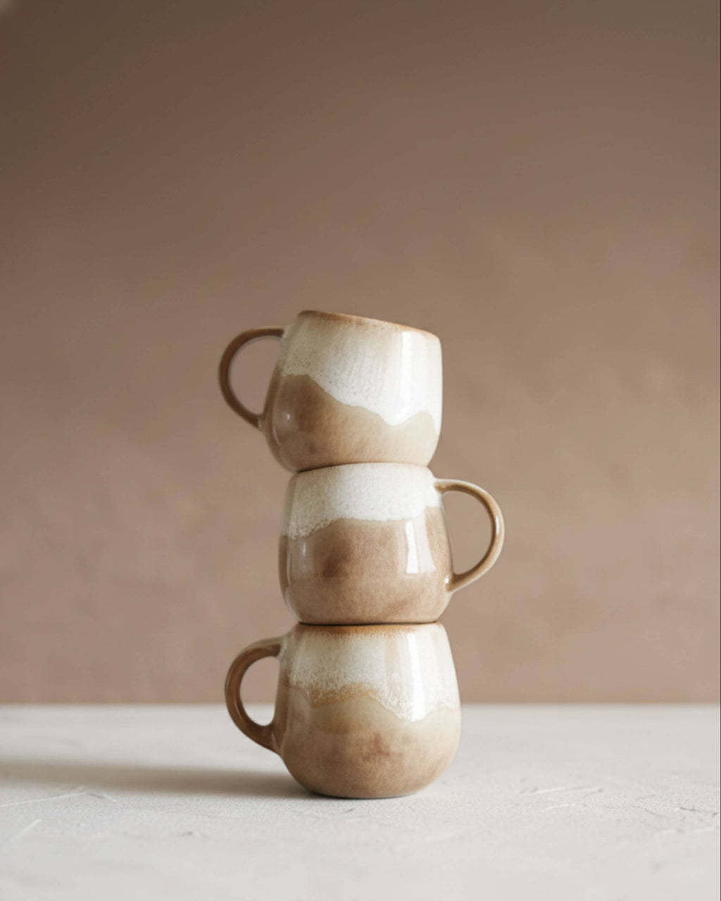 Ensemble de tasses DUNAS artisanales empilées, émail beige naturel et formes organiques.