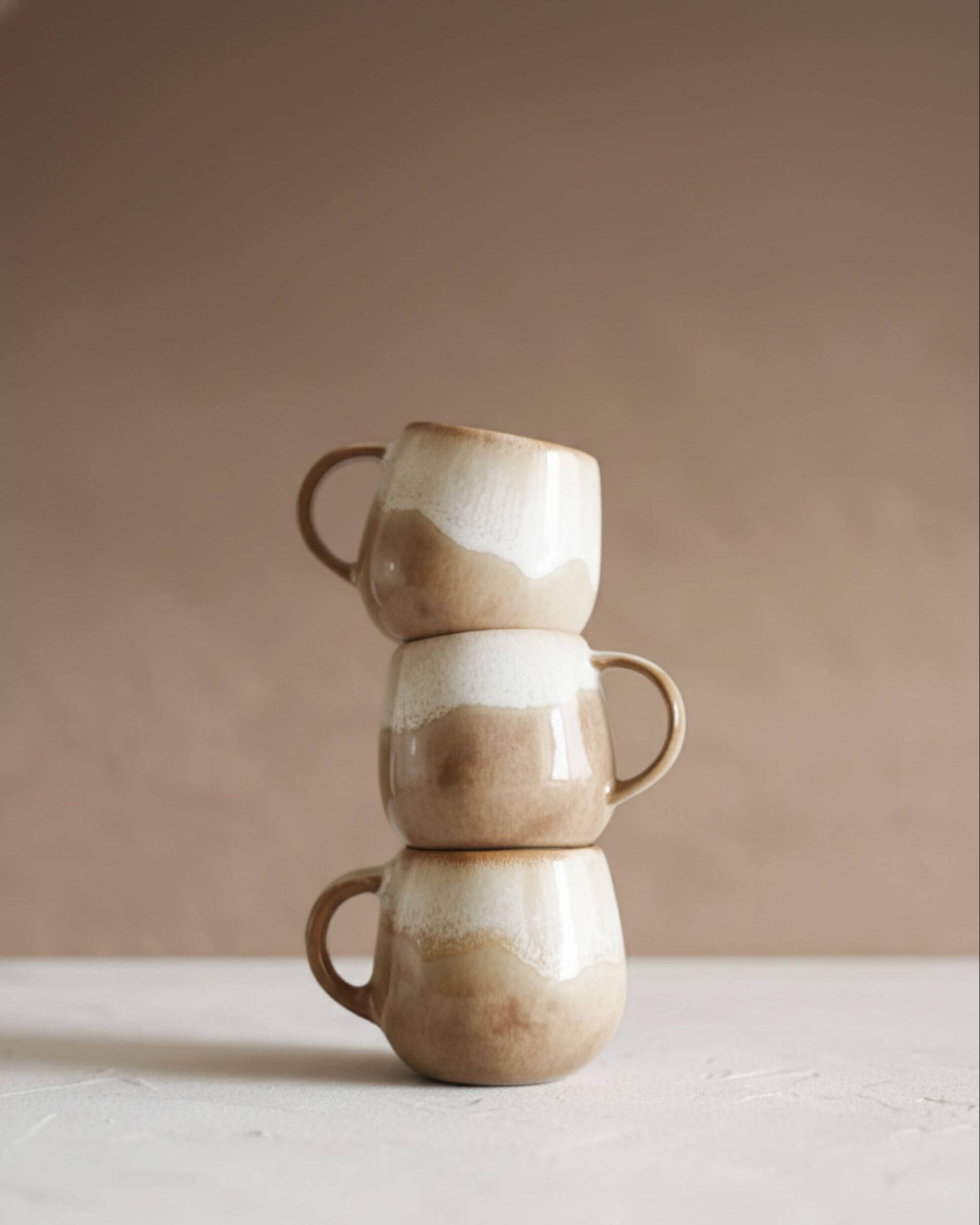 Ensemble de tasses DUNAS artisanales empilées, émail beige naturel et formes organiques.