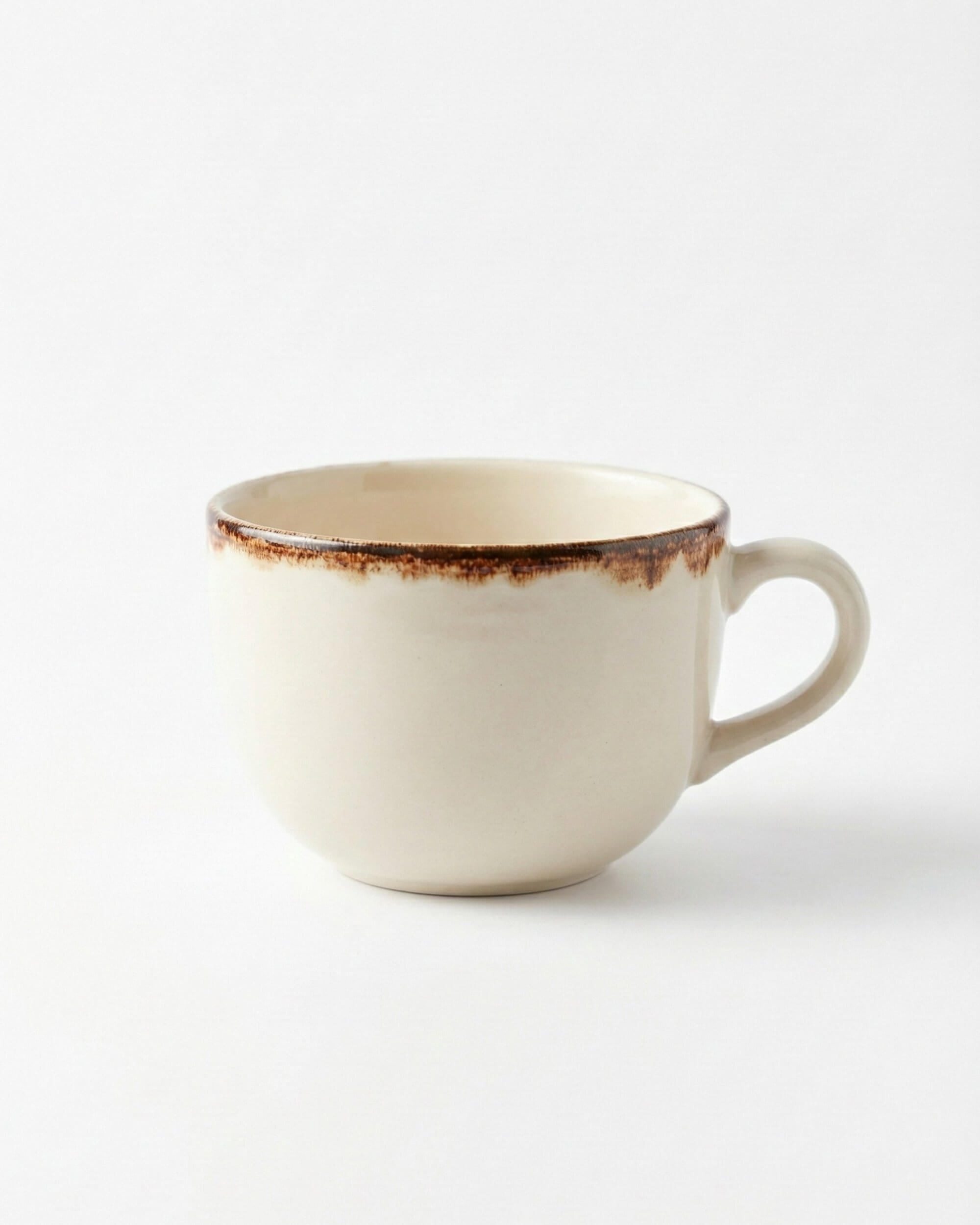 Vue de côté de la tasse déjeuner Sierra en grès beige avec une bordure marron rustique sur fond blanc.