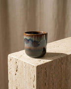 Tasse à expresso en grès émaillé Terra posée sur un bloc de pierre naturelle. Ambiance décoration artisanale et minérale.