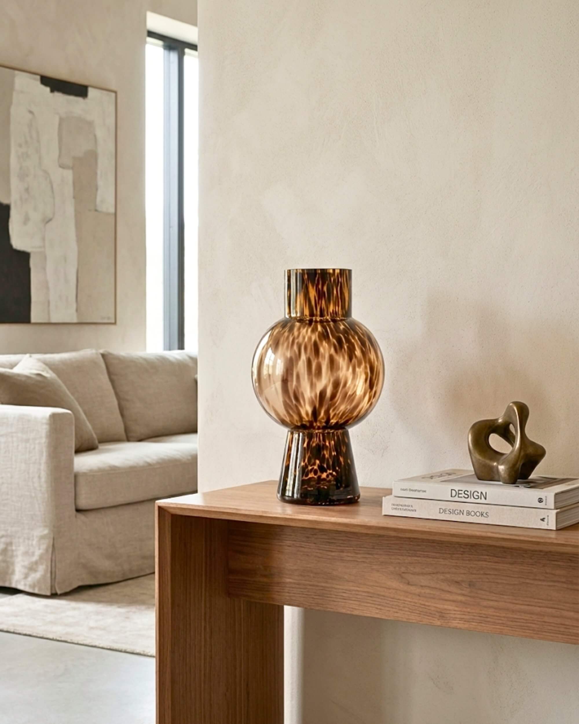 Vase Léone en verre ambré motif écaille de tortue posé sur une console en bois, ambiance salon moderne et chic.